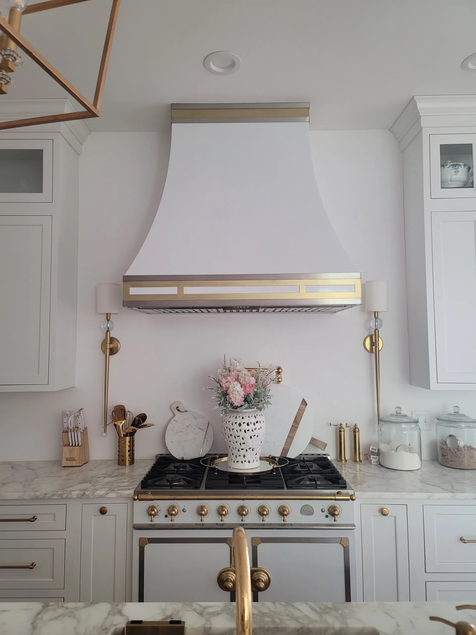 A kitchen with white cabinets and a gold hood.